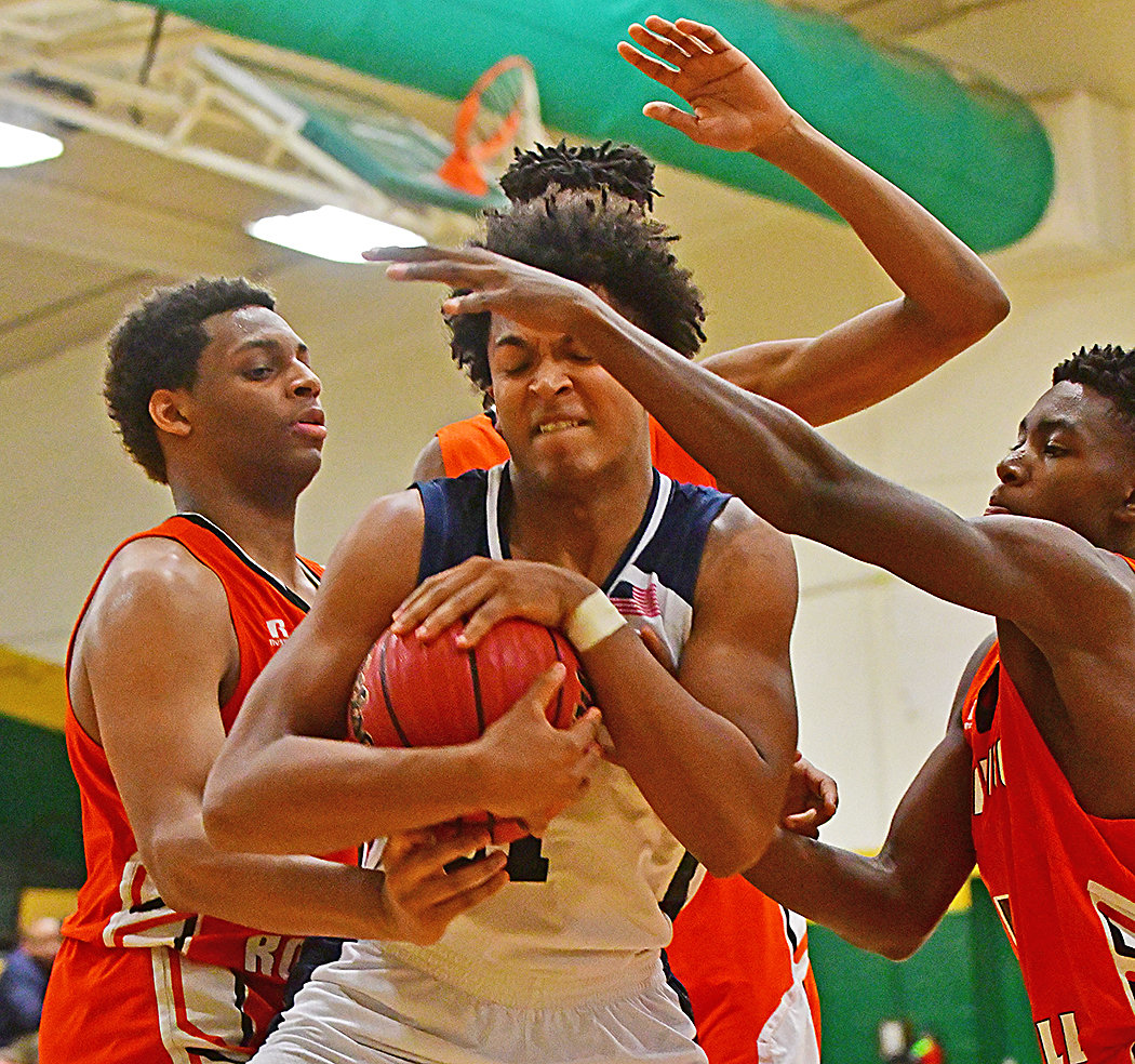 Apex Friendship Patriot Kenny Noland, center, cover s the ball up against Wallace-Rose Hill in first round action. Apex won the game 62-43.