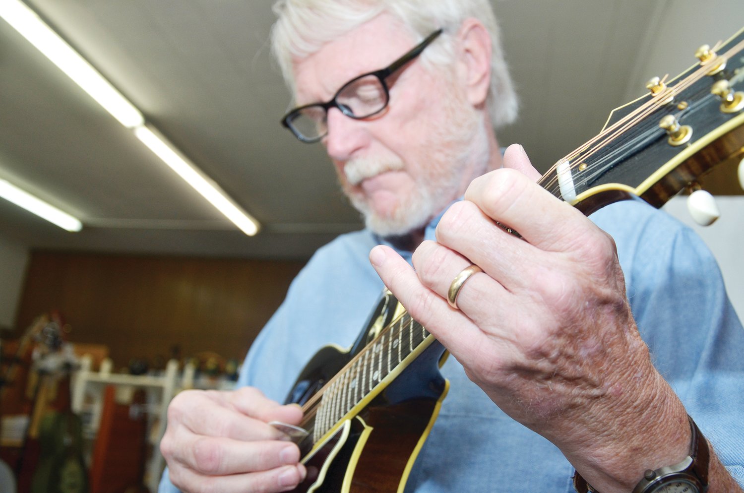 Tommy Edwards lays down a couple of riffs on the mandolin Friday at his shop after performing with a band Thursday night on the coast. Bluegrass is his favorite style.