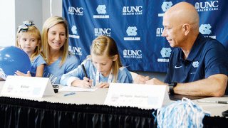 Eight-year old Kelsie Houston of Pittsboro joins the UNC's women's volleyball program. Kelsie (center) is seen signing while sister Mackenzie, mother Kimberly and UNC volleyball coach Joe Sagula look on.