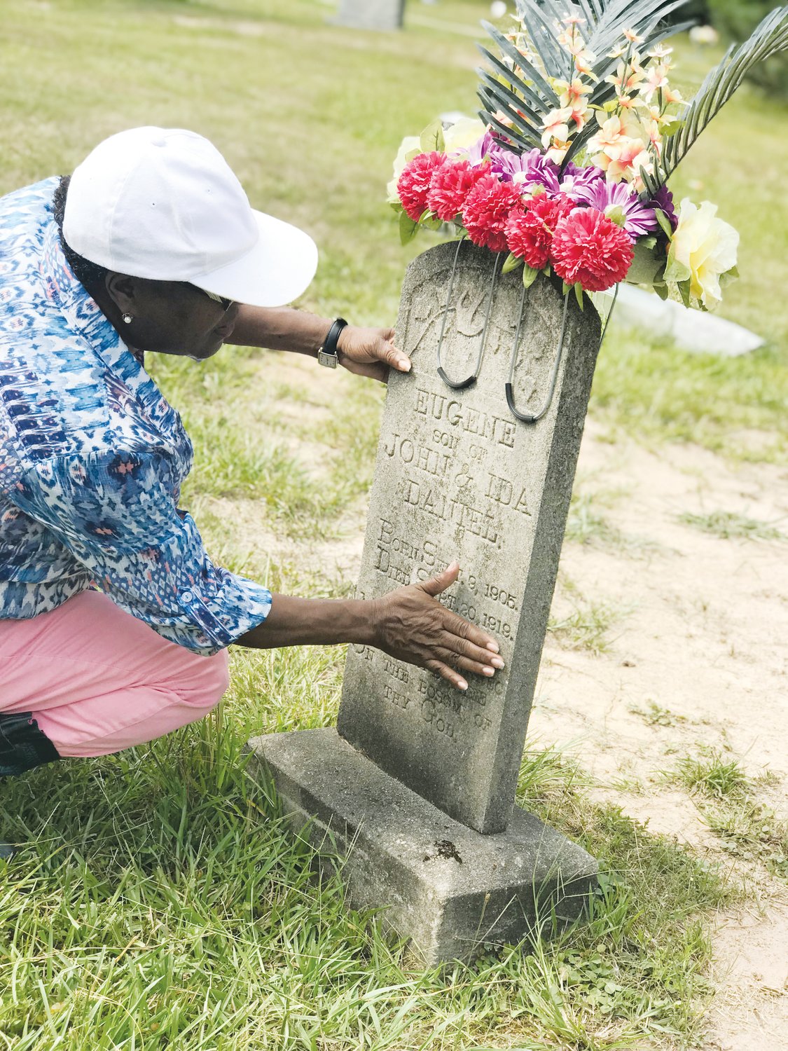Mary Nettles, the president of the Chatham Community (East) Branch of the NAACP, brushes debris off the tombstone of Eugene Daniel at New Hope Church Cemetery. Daniel was the last of Chatham County's six lynching victims. The date on his tombstone — Sept. 20, 1919 — is actually incorrect. Daniel was lynched by a group of about 50 men on Sept. 18, 1921. A group of Chatham residents are working to memorialize those lynched.