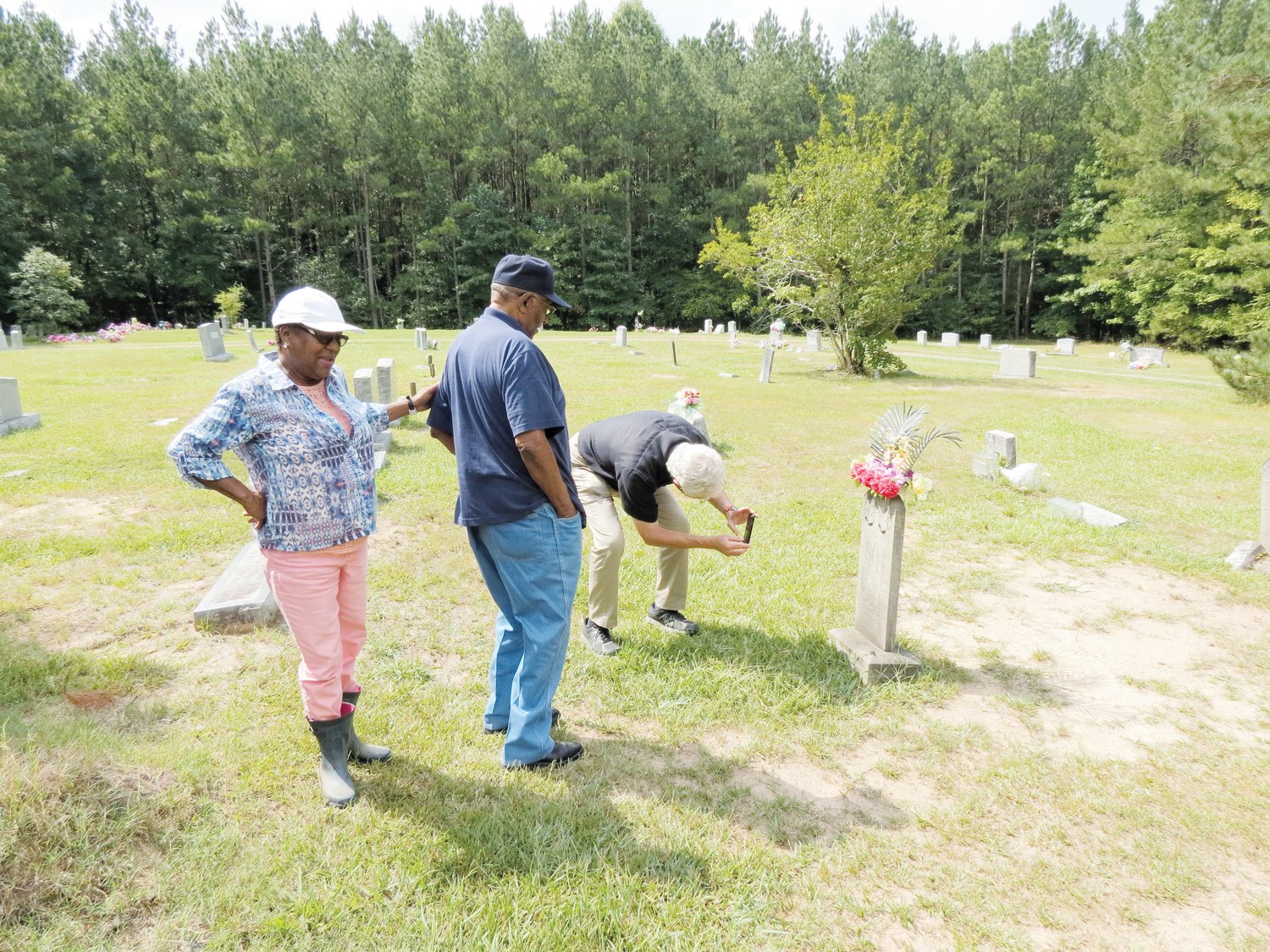 Mary Nettles (from left), the Rev. Norman T. Davis and Bob Pearson examine the tombstone and gravesite of Eugene Daniel in the New Hope Church Cemetery. Nettles is the president of the east branch of the Chatham County NAACP; Pearson serves on the branch's education committee.