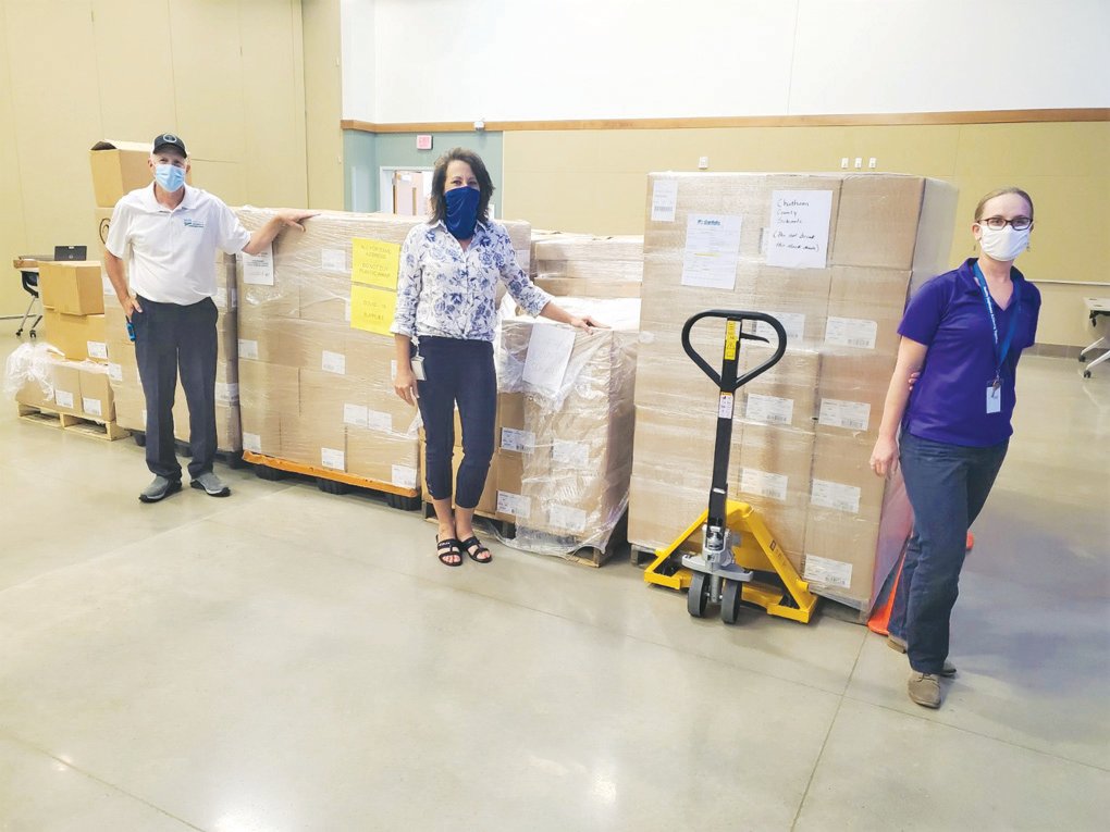 Lacee George (left), Larilee Isley and Marty Allen pose with boxes of supplies inside Pittsboro's Chatham County Agriculture & Conference Center in Pittsboro.