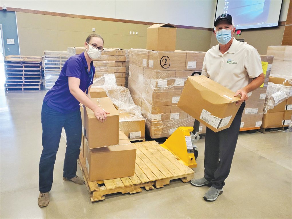 Lacee George (left) and Marty Allen work on unloading boxes of supplies at the Chatham County Agriculture & Conference Center in Pittsboro, which has been partially re-purposed during the COVID-19 pandemic.