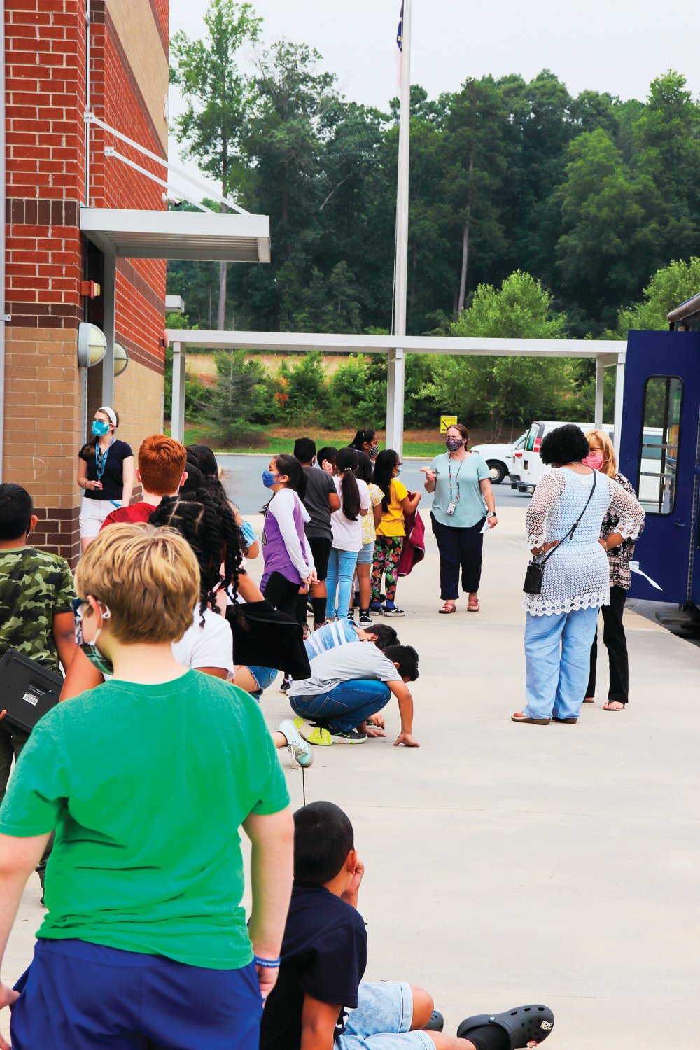 Children line up for the Bookmobile, waiting to go inside to grab some books last Tuesday at the Virginia Cross Elementary School in Siler City. Each child was able to take home some free books to read over the summer.