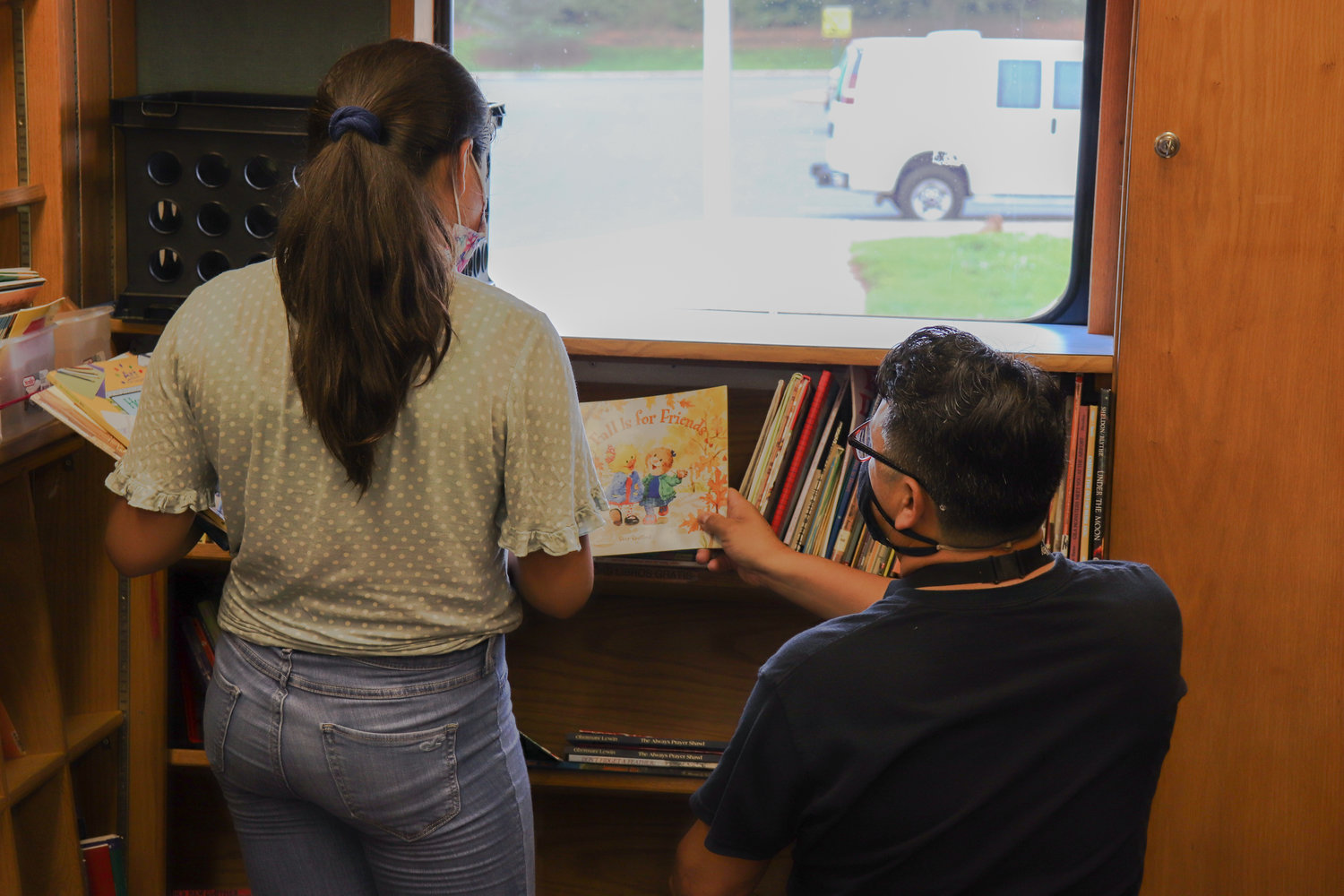 Enrique Rojas helps Melani Canela Soto identify which book she would like to take home last Tuesday in the Bookmobile. The Bookmobile carries thousands of books on board.