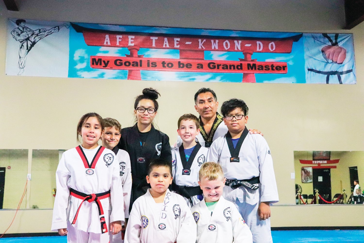 The advanced class at A.F.E. Taekwondo Fitness Academy (top row, from left to right: Eli Ara (black), Antonio Ara; middle row, from left to right: Vennus Paz, Zach Riggsbee, Fischer Pike, David Jiminez; bottom row, from left to right: Yoxander de la Cruz, Canne Applewhite) poses for a group shot following their class on Monday.