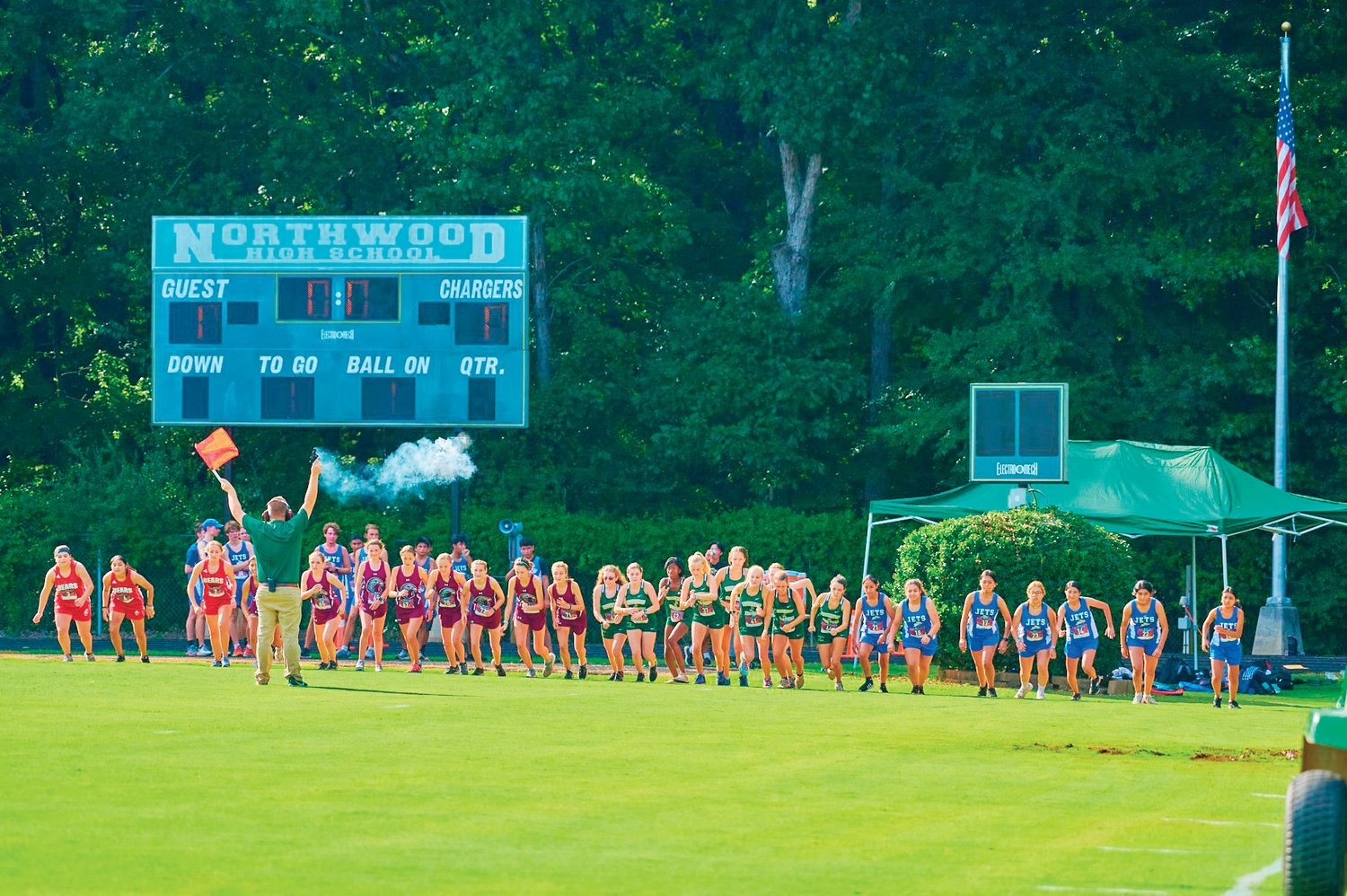 Northwood head cross country coach Cameron Isenhour (with flag) fires off the starting shot to begin the women's race at the Chatham County Championships meet last Thursday in Pittsboro. 27 runners from Chatham Central, Jordan-Matthews, Northwood and Seaforth participated in the event.