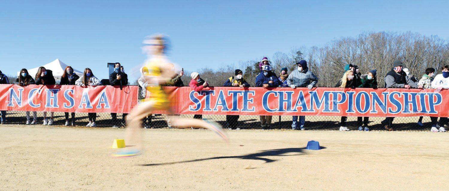 Bundled in warm clothes, spectators look on as runners approach the finish line at the NCHSAA state cross country meet in January. The two-day championship event, typically held in early November, is one of 17-plus state championship events put on by the NCHSAA each year.
