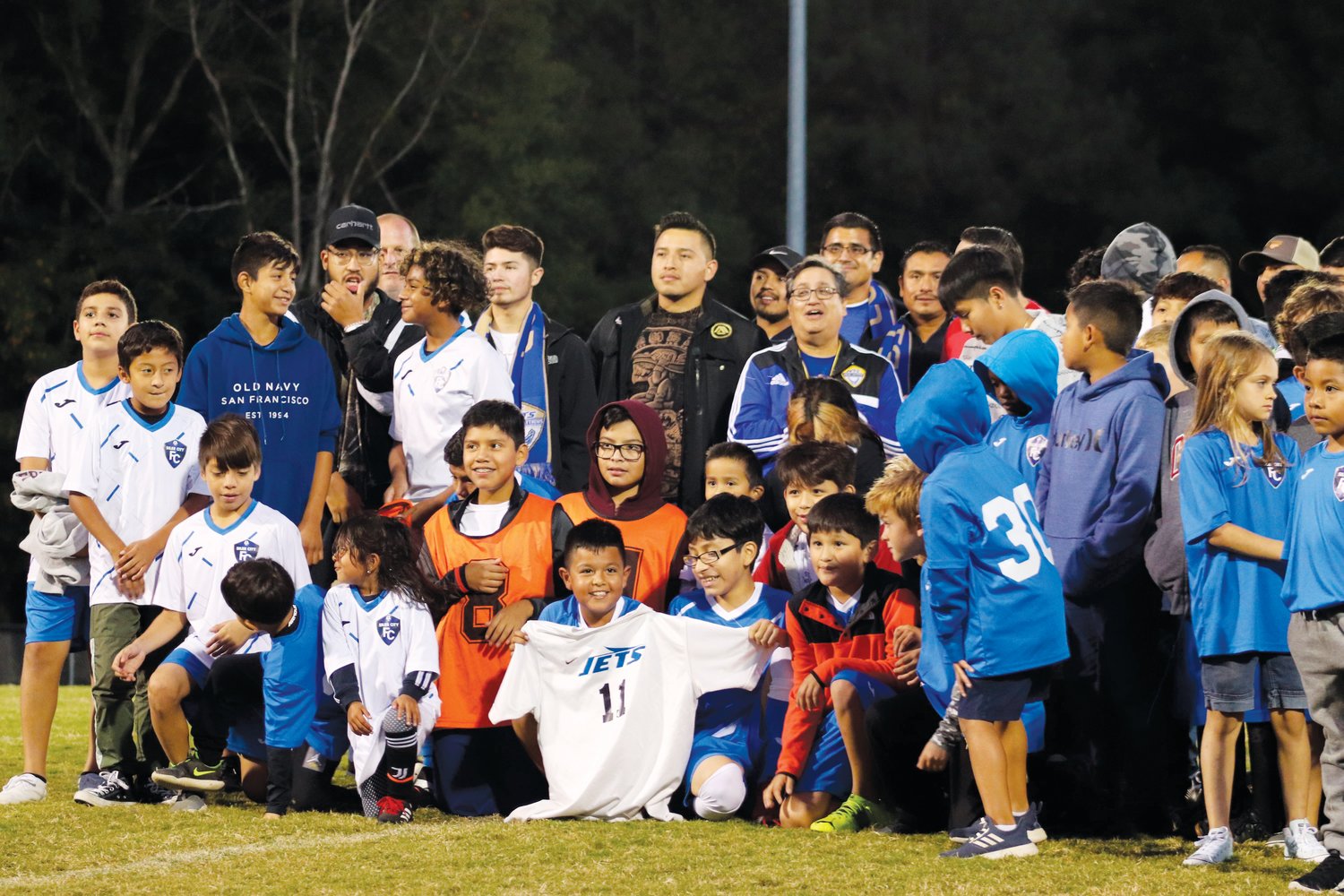 Players from Siler City Futbol Club gather around former Jordan-Matthews players at midfield during the ceremony honoring the 20th anniversary of Los Jets' creation at halftime of the Jets' 6-0 win over Cummings last Monday.
