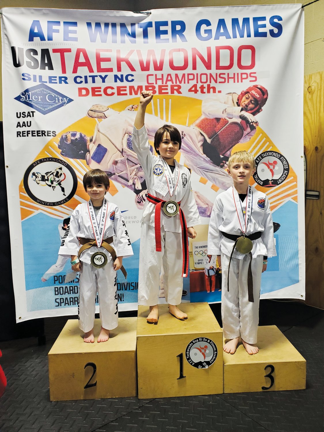 A.F.E. Taekwondo student Ace Justice (center) poses on the podium after taking first place in an event during the 2021 AFE Winter Games in Siler City last Saturday.