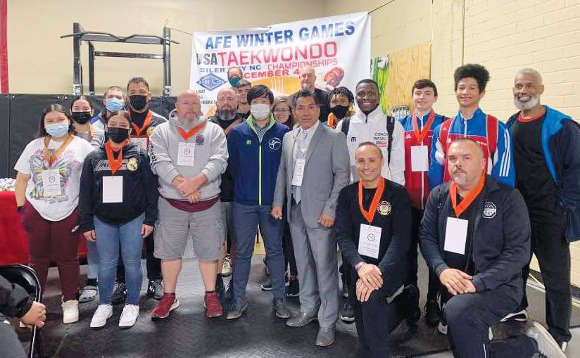 Coaches and officials, including A.F.E. Taekwondo owner Antonio Ara (gray suit, front row), pose for photos at the 4th annual AFE Winter Games in Siler City.