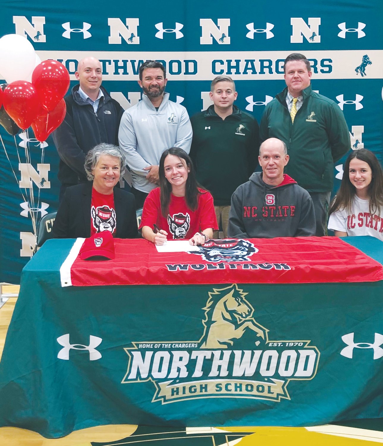 Northwood senior Caroline Murrell (center, red shirt), surrounded by her family and Northwood staff, signs her letter of intent to attend N.C. State next fall, where she'll run cross country for the Wolfpack.