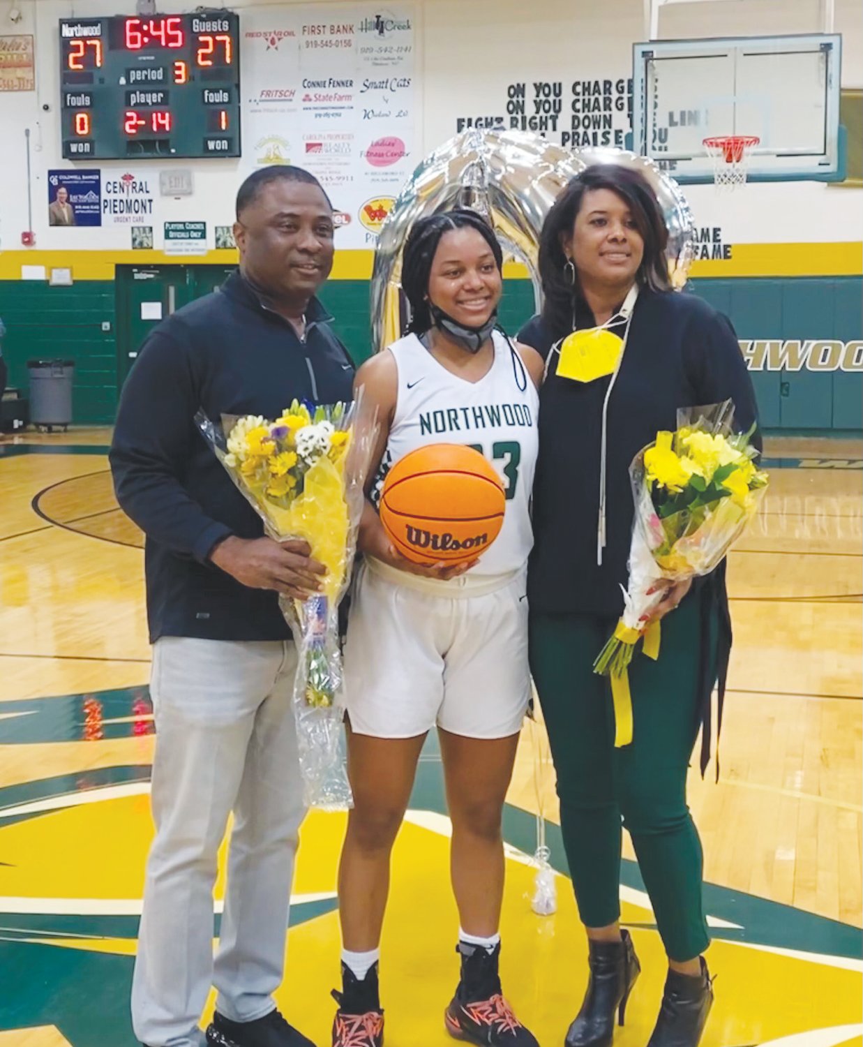 Northwood senior Olivia Porter (center) poses for photos at mid-court with her father, Larry Porter (left), and her mother, Sharmane Porter, during the third quarter of the Chargers' 59-47 win over Panther Creek last Wednesday. Porter scored her 2,000th career point in the second quarter, prompting Northwood Athletic Director Cameron Vernon to honor her during a timeout in the second half.
