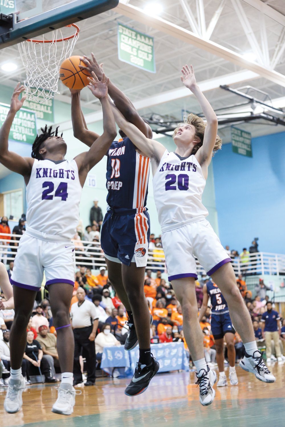 Chatham Charter juniors Aamir Mapp (24) and Adam Harvey (20) attempt to block a shot from Wilson Prep sophomore David Ellis during the Knights' 59-42 Final Four win over the Tigers last Saturday.
