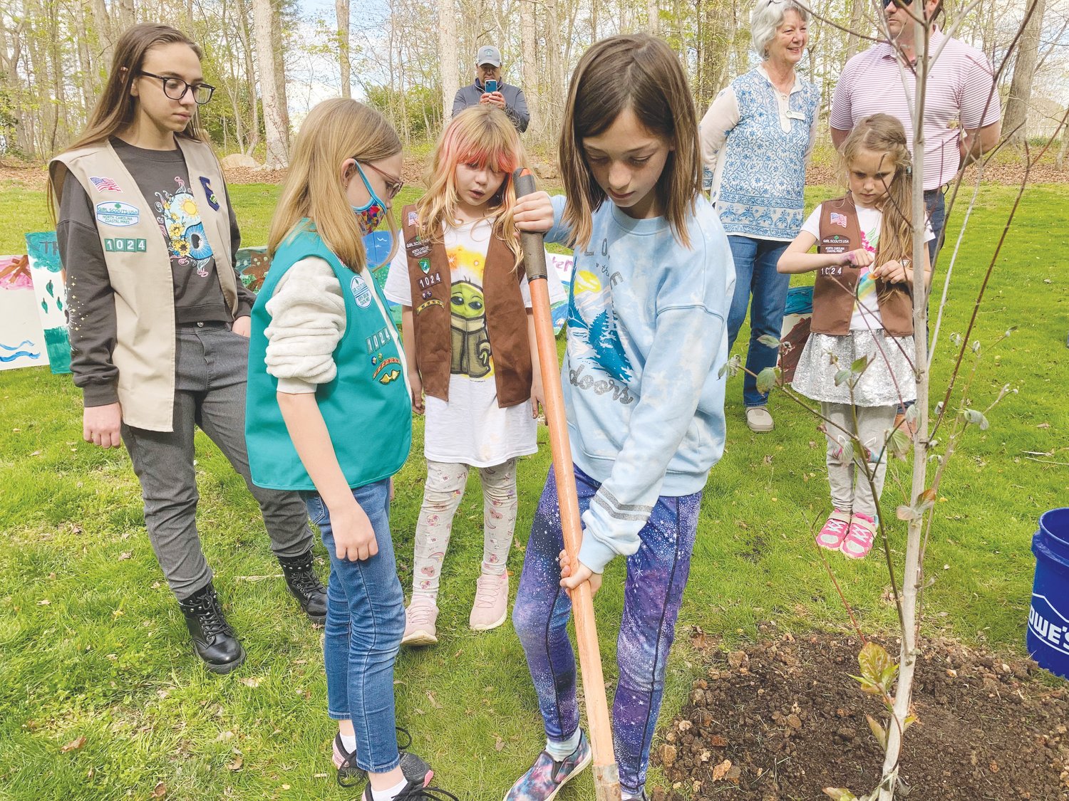 Girl Scouts from Troop 1024 shovel dirt to plant a tree for Arbor Day.