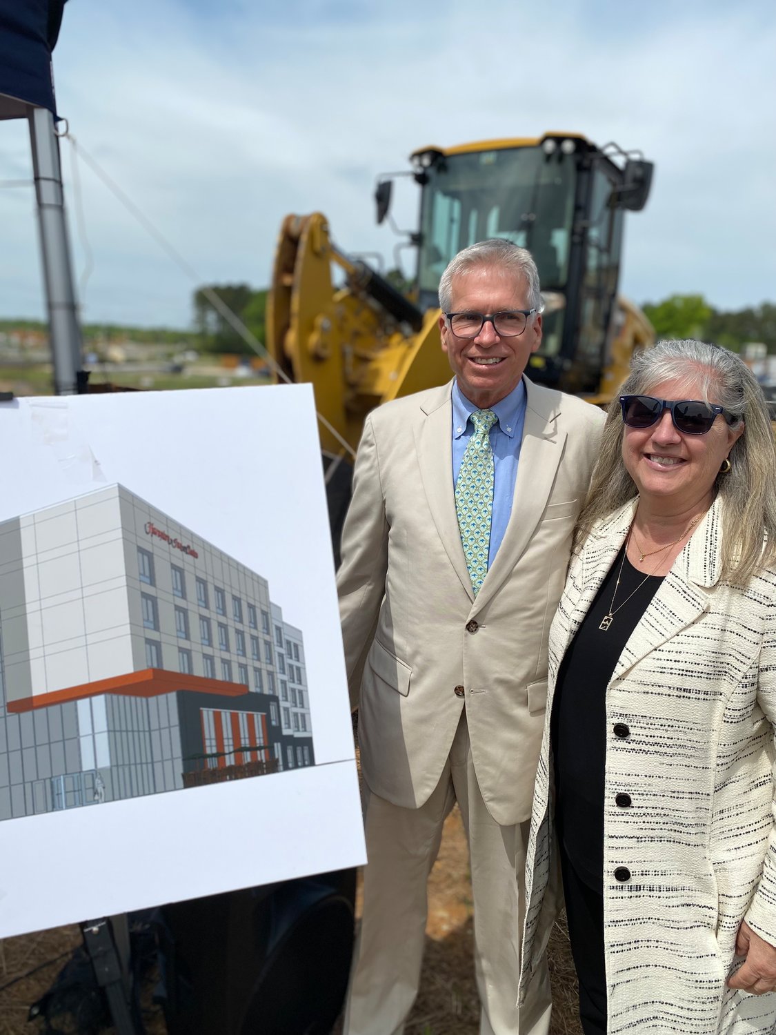 Malcolm and Sally Bryant, the co-founders of Malcolm Bryant Corporation, pose with a rendering of the 121-key Hampton Inn to be built within Mosaic at Chatham Park. Chatham County's first hotel will open its doors for guests in the fall of 2023.