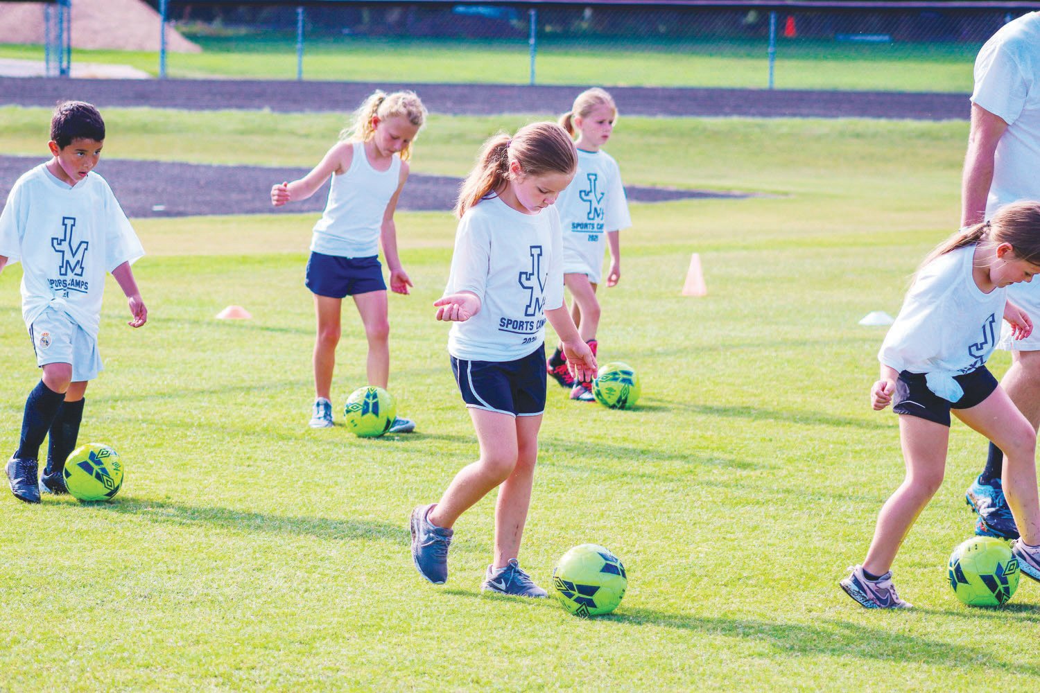 A small group of campers (from left to right: Liam Rodriguez Hutarte, June Carol Perry, Carissa Reece, Piper Cook, Ava Moore) — decked out in their camp t-shirts — practice dribbling drills on the final day of J-M's youth summer soccer camp on July 1, 2021.
