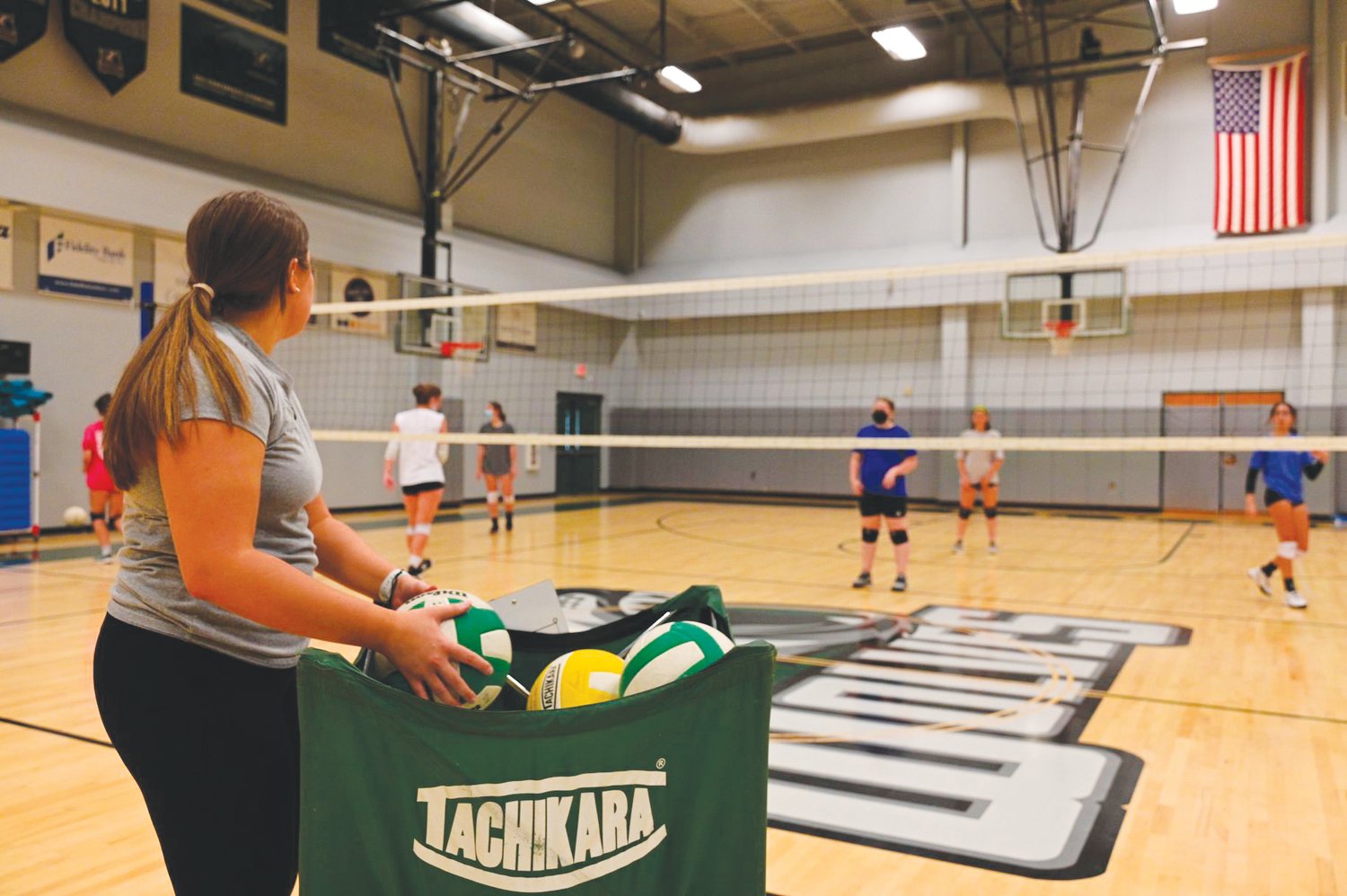 Woods Charter volleyball head coach Amanda Gough (far left) grabs balls being used for drills during her first open gym session on Monday.