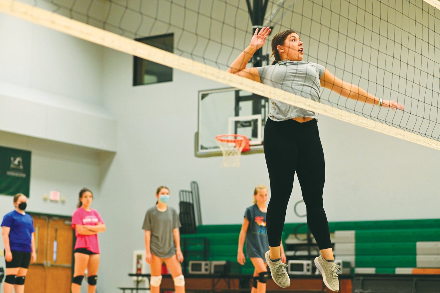 Newly hired Woods Charter volleyball coach Amanda Gough (in gray) demonstrates hitting at the net during a volleyball open gym on Monday.
