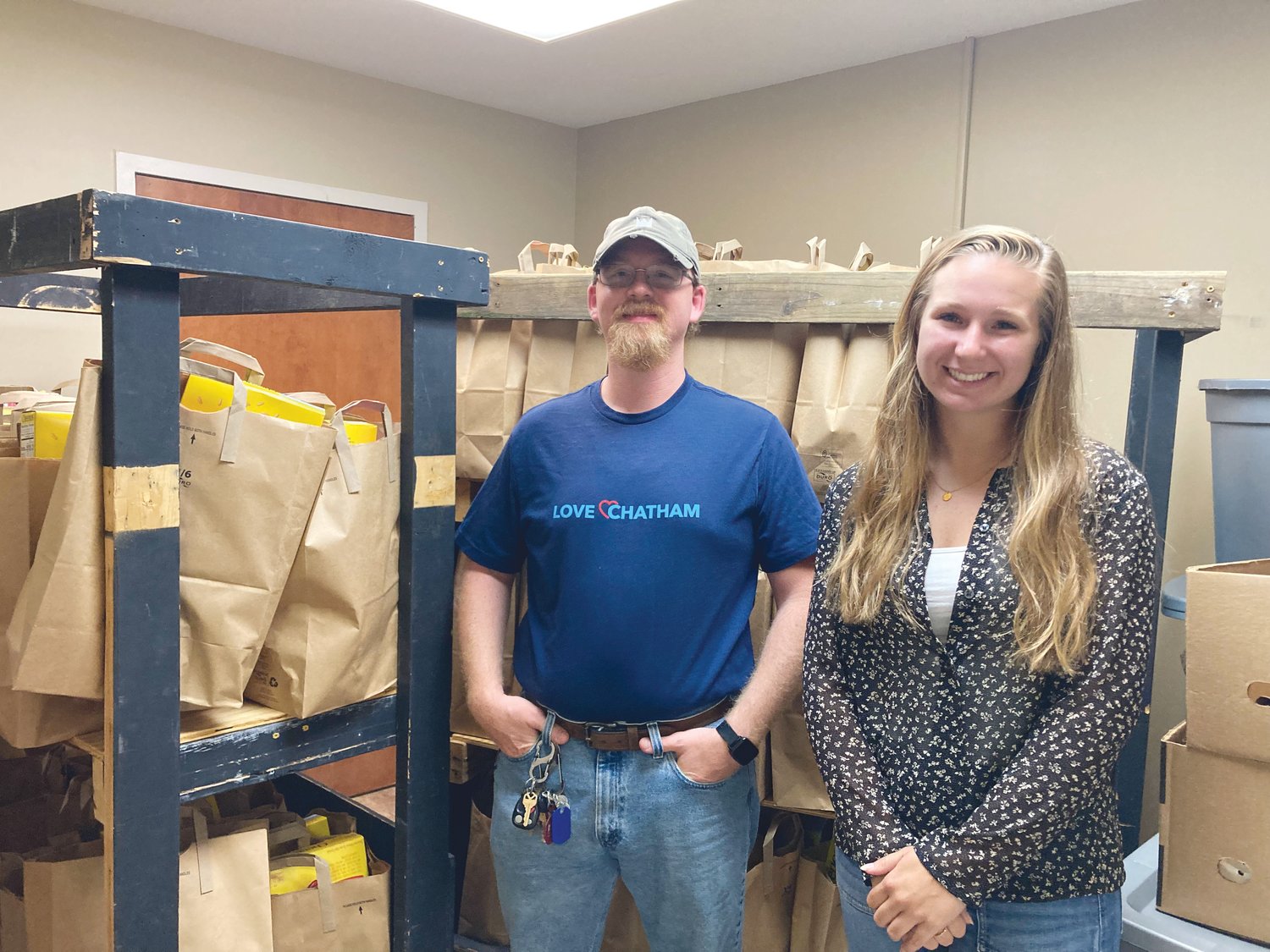 Dakota Philbrick (left) and Mary Lacey Eubanks stand in Love Chatham's food packaging room. Love Chatham distributes these meal bags each Saturday to those in need.