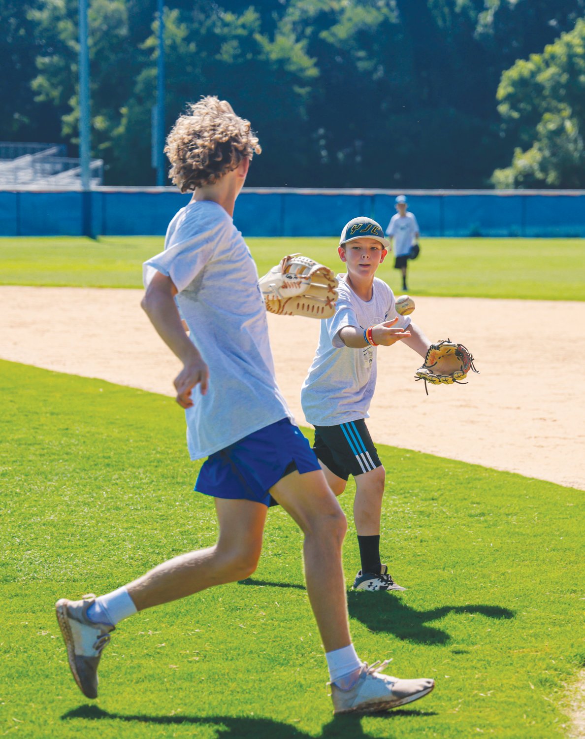 Jackson (right), a camper at Jordan-Matthews' annual baseball camp, tosses the ball to Jets junior Kelton Fuquay on the final day of camp last Thursday.
