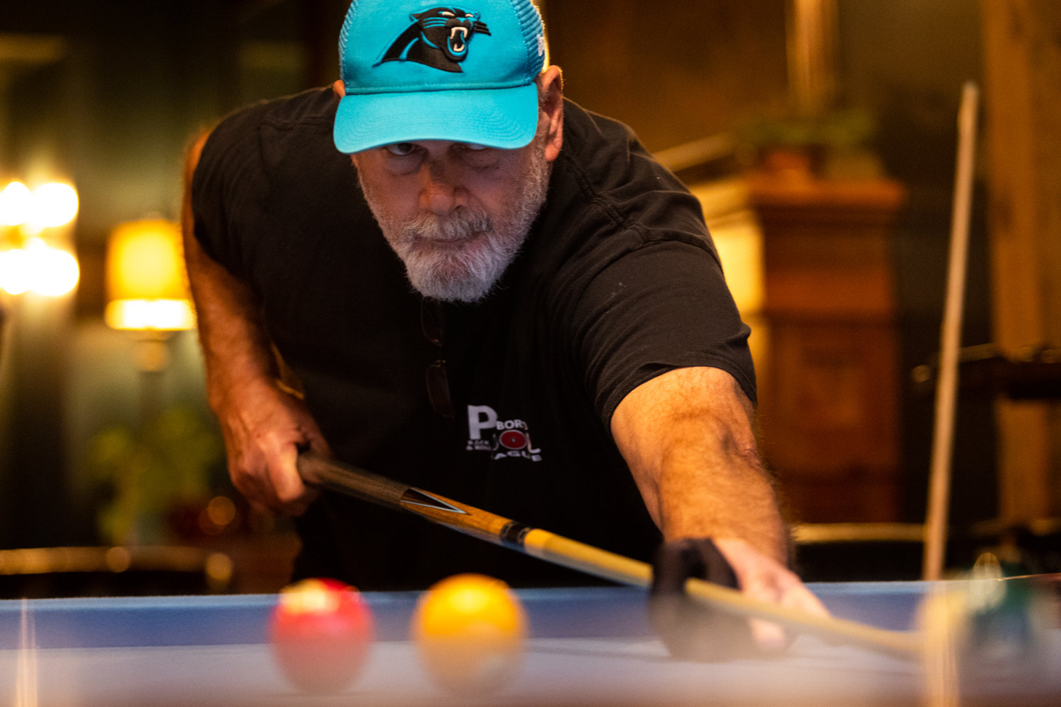 Bruce Hively, member of the Pittsboro Pool League, lines up a shot during a match against Antonio Sloan at The Sycamore at Chatham Mills.