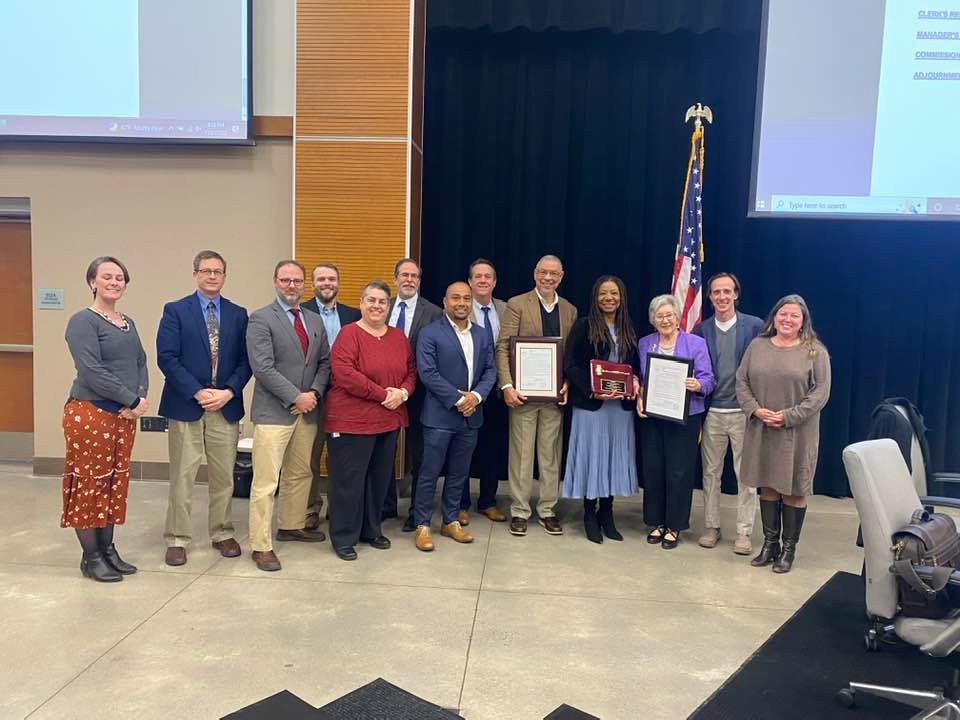 Commissioners Robert Logan (center right, tan suit)  and Diana Hales (center right, purple blazer) pose with fellow commissioners and county staff. Logan and Hales were awarded plaques for their service to Chatham County in their final meeting as members of the board on Monday, Nov. 21.