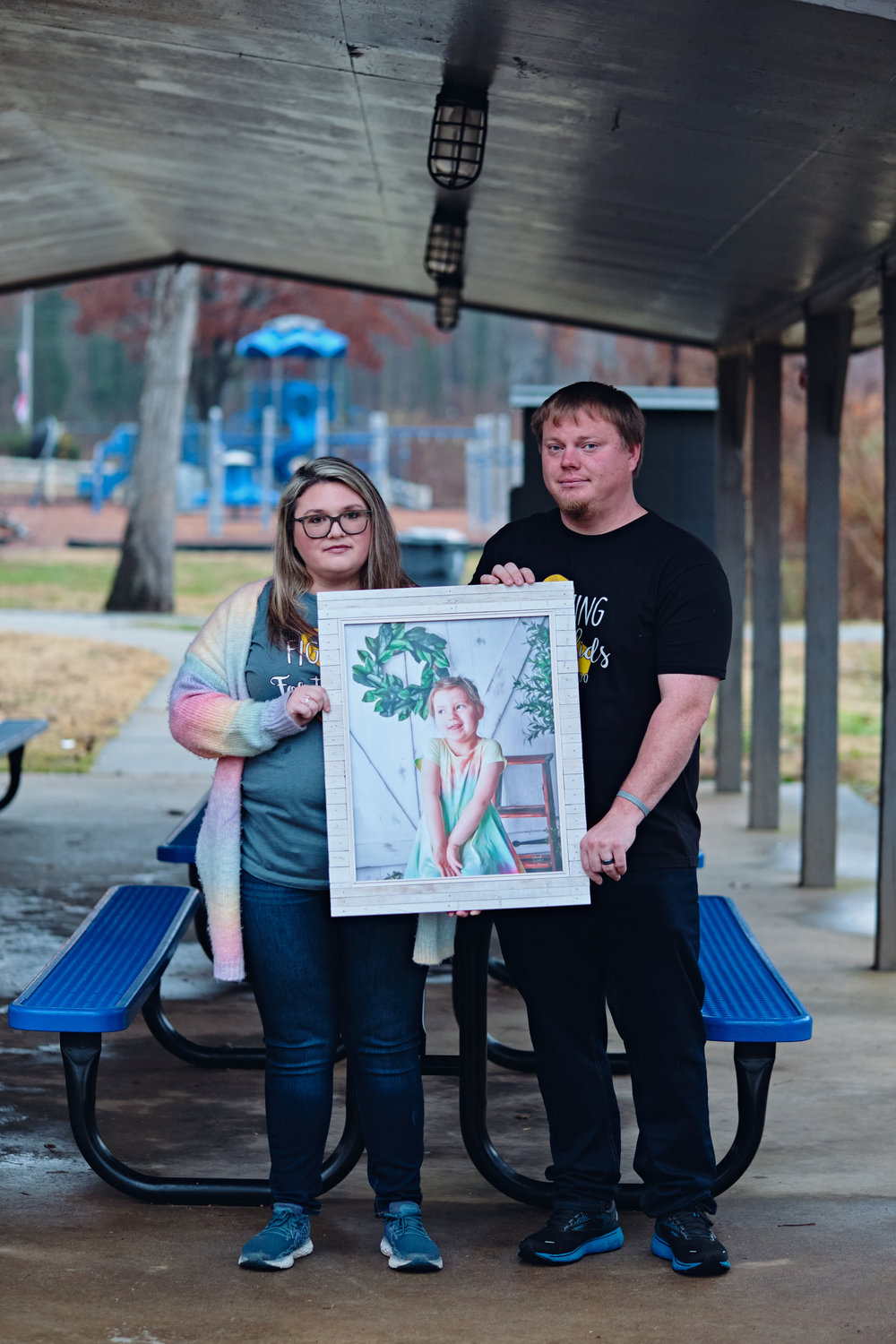 Meghan and Dusty Scoggins pose with a framed photo of their 5-year-old daughter Kenzie, who died from an aggressive childhood brain tumor called diffuse intrinsic pontine glioma (DIPG) on Sept. 18.